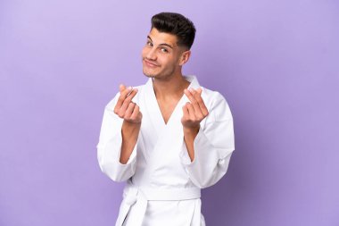 Mor arka planda karate yapan genç beyaz adam para hareketi yapıyor.