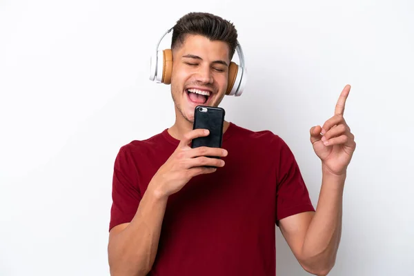 Νεαρός Καυκάσιος Άνδρας Απομονωμένος Λευκό Φόντο Ακούγοντας Μουσική Κινητό Και — Φωτογραφία Αρχείου