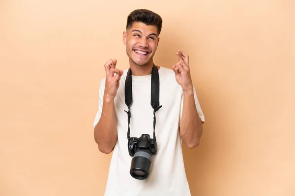 Jovem Fotógrafo Caucasiano Isolado Fundo Bege Com Dedos Cruzando — Fotografia de Stock