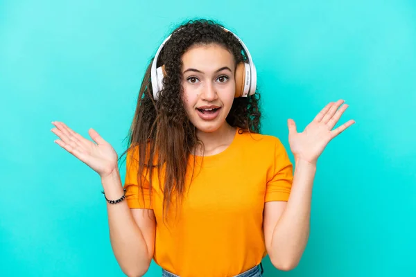 Mujer Árabe Joven Aislada Sobre Fondo Azul Sorprendida Escuchando Música —  Fotos de Stock