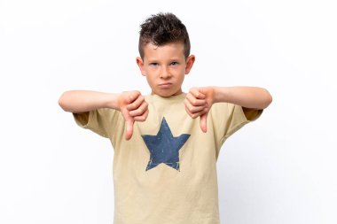 Beyaz arka planda izole edilmiş küçük beyaz çocuk baş parmağını iki eliyle aşağı gösteriyor.
