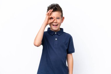 Beyaz arka planda izole edilmiş küçük beyaz çocuk parmaklarıyla tamam işareti gösteriyor.