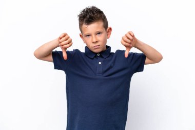 Beyaz arka planda izole edilmiş küçük beyaz çocuk baş parmağını iki eliyle aşağı gösteriyor.