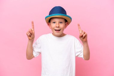 Pembe arka planda izole edilmiş şapka takan küçük beyaz çocuk harika bir fikre işaret ediyor.
