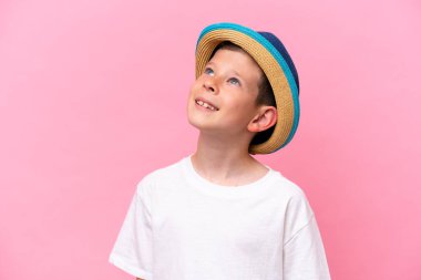 Pembe arka planda izole edilmiş şapka takan beyaz bir çocuk.