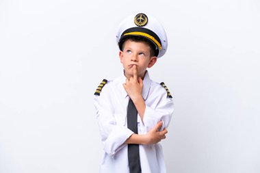 Küçük pilot çocuk beyaz arka planda izole edilmiş, yukarı bakarken şüpheleri var.
