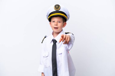 Küçük pilot çocuk beyaz arka planda izole edilmiş, şaşırmış ve ön tarafı işaret ediyor.