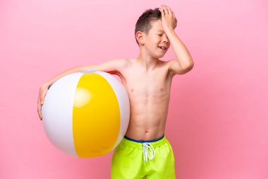 Pembe arka planda izole edilmiş bir plaj topu tutan küçük beyaz çocuk bir şey fark etti ve çözüme niyetlendi.