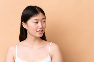 Genç Çinli kadın bej arka planda izole edilmiş. Portre