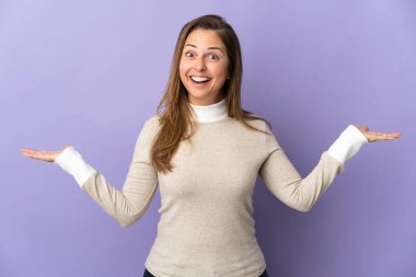 Orta yaşlı Brezilyalı kadın, mor arka planda izole edilmiş, şok olmuş bir yüz ifadesi var.
