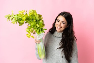 Mavi arka planda izole edilmiş kereviz tutan beyaz bir kadın.