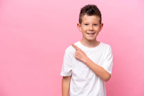 Pequeño Chico Caucásico Aislado Sobre Fondo Rosa Apuntando Hacia Lado —  Fotos de Stock