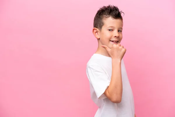 Pequeno Menino Caucasiano Isolado Fundo Rosa Apontando Para Lado Para — Fotografia de Stock