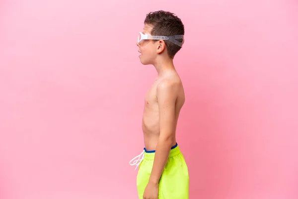 一个戴着潜水护目镜的高加索小男孩 带着粉色背景的隔离镜 侧身大笑着 — 图库照片