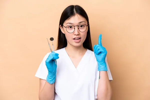 牙医中国女人拿着因米黄色背景而被隔离的工具 认为这是一个指指点点的想法 — 图库照片