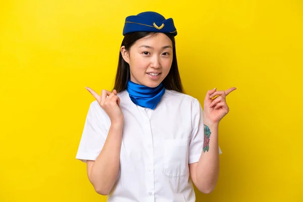 飞机上的中国妇女空姐被黄色背景隔离 手指指向侧边 很快乐 — 图库照片