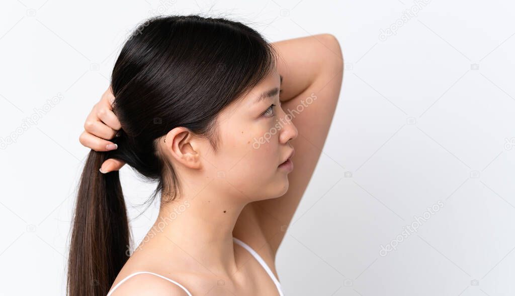 Young Chinese woman isolated on white background touching her hair. Close up portrait
