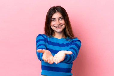 Pembe arka planda izole edilmiş genç beyaz kadın bir ilan vermek için avucunun içinde hayali bir fotokopi makinesi tutuyor.