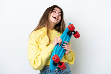 Beyaz arka planda izole edilmiş beyaz tenli genç bir kadın mutlu bir ifadeyle paten kayıyor.