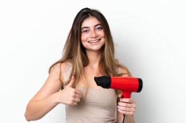 Young caucasian woman holding a hairdryer isolated on white background with thumbs up because something good has happened
