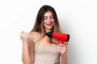 Young caucasian woman holding a hairdryer isolated on white background celebrating a victory