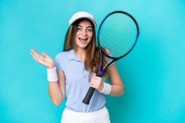 Genç tenisçi kadın mavi arka planda izole edilmiş ve şok olmuş bir yüz ifadesi var.