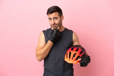 Pembe arka planda izole edilmiş genç bisikletçi.