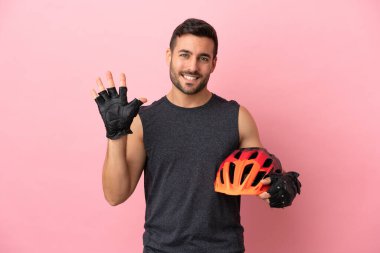 Pembe arka planda izole edilmiş genç bisikletçi parmaklarıyla beşi sayıyor