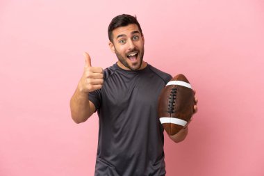 Young caucasian man playing rugby isolated on pink background with thumbs up because something good has happened