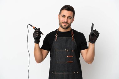 Dövme sanatçısı beyaz arka planda izole edilmiş ve en iyinin işareti olarak parmağını kaldırıyor.