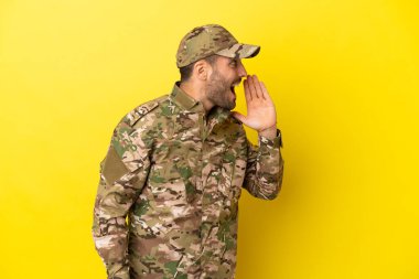 Sarı arka planda izole edilmiş asker ağzı sonuna kadar açık bağırıyor.