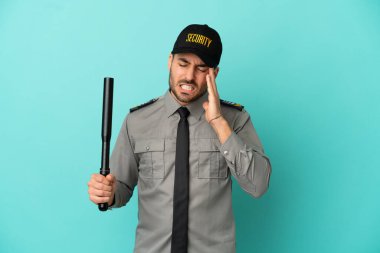 Mavi arka planda başı ağrıyan genç bir güvenlik görevlisi var.