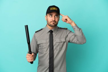 Genç güvenlik görevlisi mavi arka planda izole edildi. Şüpheleri ve düşünceleri var.