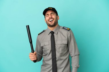 Genç güvenlik görevlisi mavi arka planda izole edilmiş gülüyor.