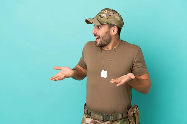 Military with dog tag over isolated on blue background with surprise facial expression