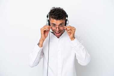 Tele pazarlamacı Brezilyalı adam kulaklıkla çalışıyor. Beyaz arka planda gözlüklü ve şaşırmış.