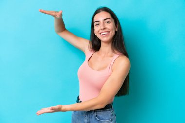 Mavi arka planda izole edilmiş beyaz bir kadın ilan vermek için kopyalama alanı tutuyor.