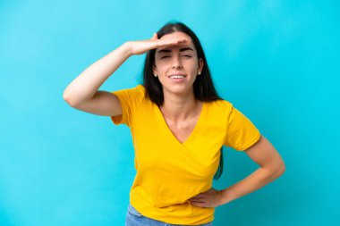 Kafkasyalı genç bir kadın mavi arka planda izole edilmiş. Bir şeye bakmak için uzaklara bakıyor.