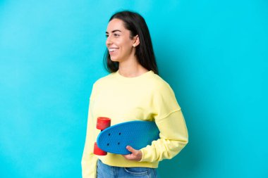 Mavi arka planda paten kayan beyaz bir kadın.