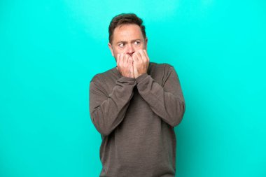 Orta yaşlı beyaz bir adam mavi arka planda izole edilmiş gergin ve korkmuş bir şekilde elleriyle suni teneffüs yapıyor.