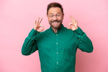 Pembe arka planda izole edilmiş orta yaşlı beyaz bir adam iki eliyle 