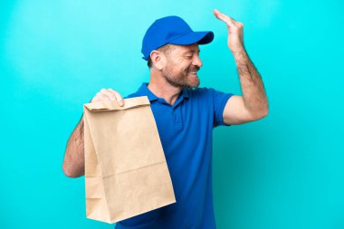 Orta yaşlı bir adam mavi arka planda izole edilmiş bir paket yiyecek alıyor. Bir şeyin farkına varıyor ve çözümü arıyor.