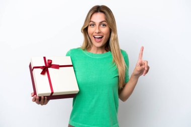 Genç Uruguaylı kadın elinde beyaz arka planda izole edilmiş bir hediye tutuyor. Harika bir fikre işaret ediyor.