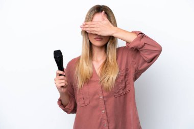 Şarkıcı Uruguaylı kadın, beyaz arka planda el ele kapalı bir mikrofonu kaldırıyor. Bir şey görmek istemiyorum.