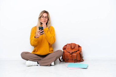 Bir katta oturan Uruguaylı öğrenci kadın beyaz arka planda izole edilmiş düşünüyor ve bir mesaj gönderiyor.