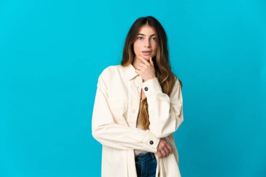 Kafkasyalı genç bir kadın mavi arka planda soyutlanmış düşünüyor.