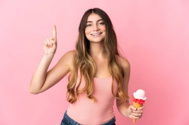 Pembe arka planda izole edilmiş kornet dondurmalı beyaz kadın harika bir fikre işaret ediyor.