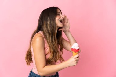 Pembe arka planda izole edilmiş, ağzı sonuna kadar açık bağıran, kornet dondurmalı beyaz bir kadın.