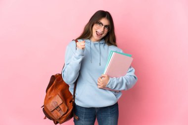 Pembe arka planda izole edilmiş genç bir öğrenci zaferi kutluyor.