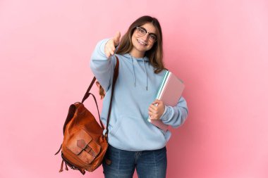 Pembe arka planda izole edilmiş genç bir bayan iyi bir anlaşma için el sıkışıyor.